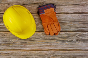 Construction site safety protective hard hat safety gloves on wooden background by . 